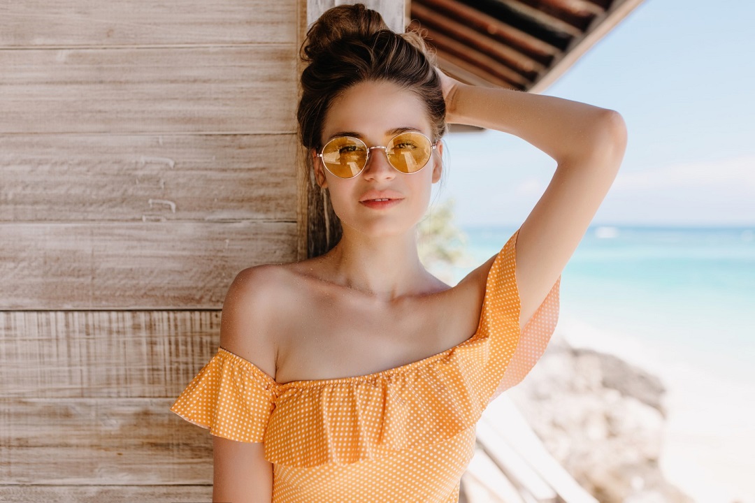 Fashionable girl in stylish sunglasses spending leisure time at beach. Outdoor photo of enthusiasti